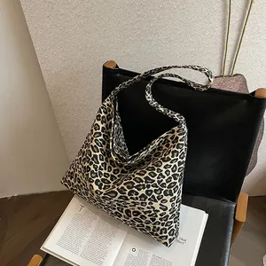 Close-up of leopard print canvas tote bag on a black leather chair with soft lighting