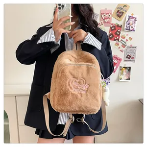 Detail of plush brown backpack with heart embroidery and cute doll charm for school
