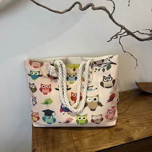 Detail of pink canvas tote bag with cartoon owl prints and thick white cotton rope handles
