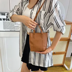 Détail de la pochette téléphone en cuir grainé marron avec gaufrage et bandoulière