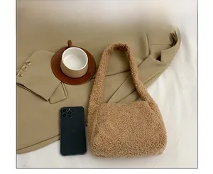 Close-up of khaki fleece handbag showing soft texture compared to a mobile phone
