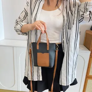 Détail d'un mini sac cabas en similicuir noir et marron avec bandoulière amovible