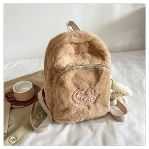 Close-up of khaki plush backpack with heart embroidery and star charm on soft background