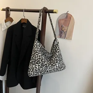 Detailed view of leopard print canvas shoulder bag styled on a rack with a black blazer
