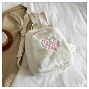 Close-up of white plush backpack featuring pink heart embroidery and soft faux fur texture