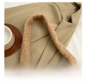 Close-up of wide plush shoulder strap on a khaki faux shearling tote bag