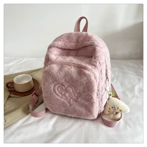 Detailed view of pink plush backpack with heart embroidery and cloud charm on bed