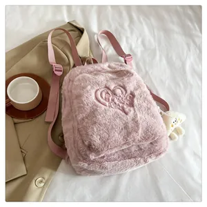 Detail of pink plush backpack featuring heart embroidery and white monster charm