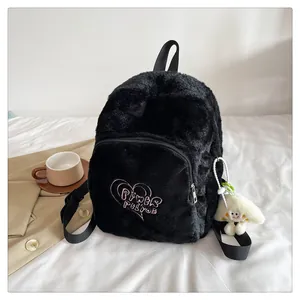 Detail of black plush backpack with pink heart embroidery and cute cartoon pendant