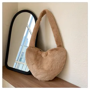Detailansicht einer braunen herzförmigen Plüsch-Schultertasche auf einem Holzregal