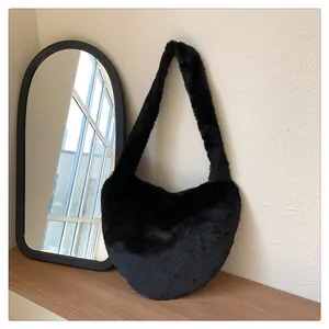 Detailaufnahme der weichen schwarzen Plüsch-Schultertasche auf einem Holzregal mit Spiegel