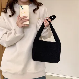 Close-up of black fuzzy faux fur tote bag showing plush sherpa texture on a shoulder strap