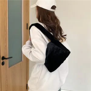 Detail of soft black faux fur shoulder bag worn by model showing plush texture and wide strap