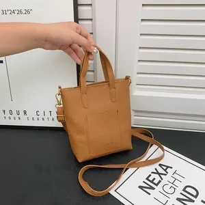 Détail du sac bandoulière en similicuir marron grainé avec doubles anses et logo fashion