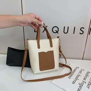 Détails du mini sac bandoulière bicolore avec texture cuir grainé et logo gravé