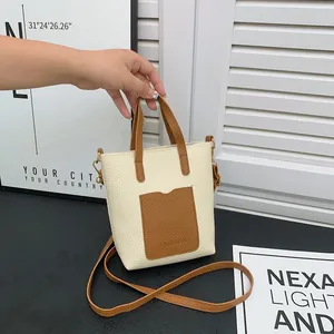 Détail du cuir synthétique grainé et des coutures bicolores sur une mini pochette mobile