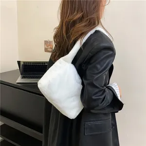 Lifestyle view of white faux fur shoulder bag worn as a cozy winter underarm accessory