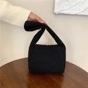 Close-up of the soft black faux shearling texture and wide handle on a winter tote bag