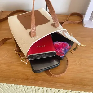 Petit sac de téléphone en similicuir blanc et marron posé sur une table en bois
