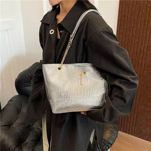 Silver crocodile texture tote bag with gold chain and deer charm on a model's shoulder