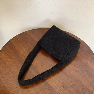 Detail of black fluffy lamb wool shoulder bag showing soft texture on a wooden table