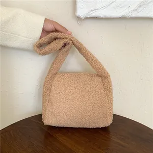 Close-up of beige fluffy shearling tote bag showing soft fuzzy texture and handle