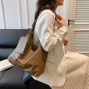 Detail of tan faux leather tote bag with knot strap and matching mini zipper pouch accessory