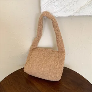 Detail shot of light brown faux shearling shoulder bag on a rustic wood surface