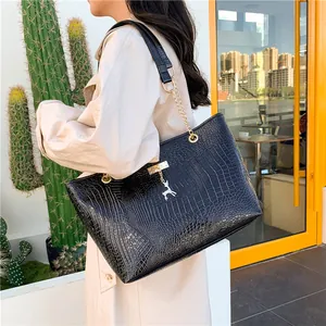 Chic black crocodile pattern tote bag with gold deer pendant shown on a model outdoors