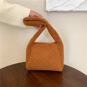 Detail of warm caramel lamb wool handbag texture on a dark wood table