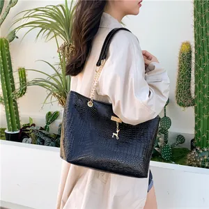 Detail of black crocodile pattern tote bag featuring gold hardware and deer charm pendant