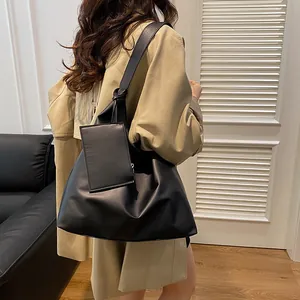 Detail of minimalist black tote bag with knotted shoulder strap and matching pouch attachment