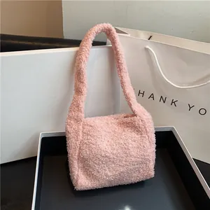 Close-up of pink faux fur plush shoulder bag with soft curly teddy texture and handles