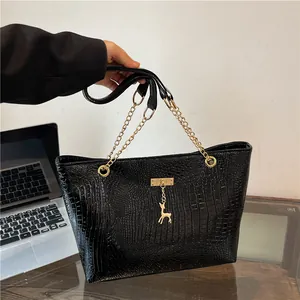 Close-up of black crocodile pattern tote bag with gold chain and deer charm detail