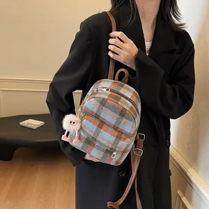 Detail of plaid wool backpack with leather straps and cute plush monster pendant accessory