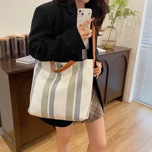 Détail d'un grand sac cabas en toile à rayures avec bandoulière marron et finitions soignées
