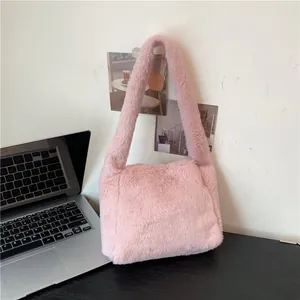Detailed close-up of pink faux fur shoulder bag texture with wide strap on a desk