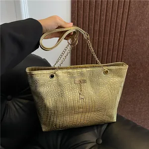 Detail of metallic gold crocodile embossed tote bag with a small deer charm
