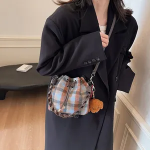 Detail of vintage plaid woolen bucket bag with drawstring and cute teddy bear charm