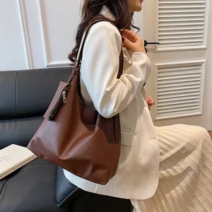 Close-up of brown faux leather tote bag with side zipper pouch and wide shoulder strap