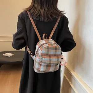 Detail of checkered wool mini backpack with leather straps and cute plush monster charm