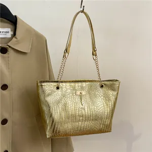 Detail of gold crocodile embossed tote bag with deer charm and chain shoulder strap