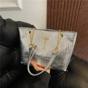 Detail of silver crocodile pattern tote bag with gold deer pendant and chain handle