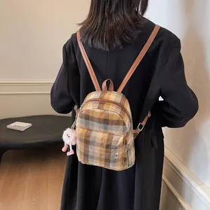 Detail of wool plaid backpack with brown leather straps and pink plush pendant