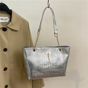 Detail of silver crocodile embossed tote bag with gold chain strap and deer pendant