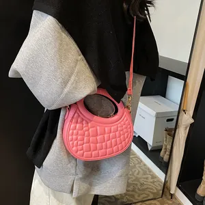 Detailed view of pink croc-embossed half-moon bag featuring a round cutout handle