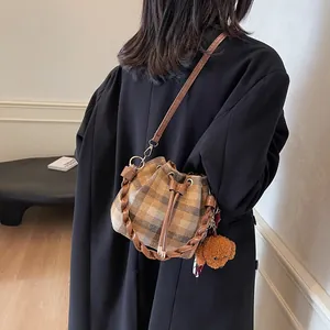 Detail view of a vintage plaid drawstring bucket bag featuring a cute plush puppy charm