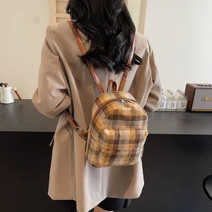 Detail of wool plaid mini backpack featuring brown leather straps and adjustable buckles