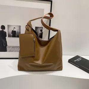 Detail of a brown vintage hobo tote bag with a small matching zipper pouch on a white surface
