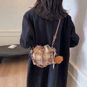 Detail of vintage plaid bucket bag with braided handle and cute teddy bear charm